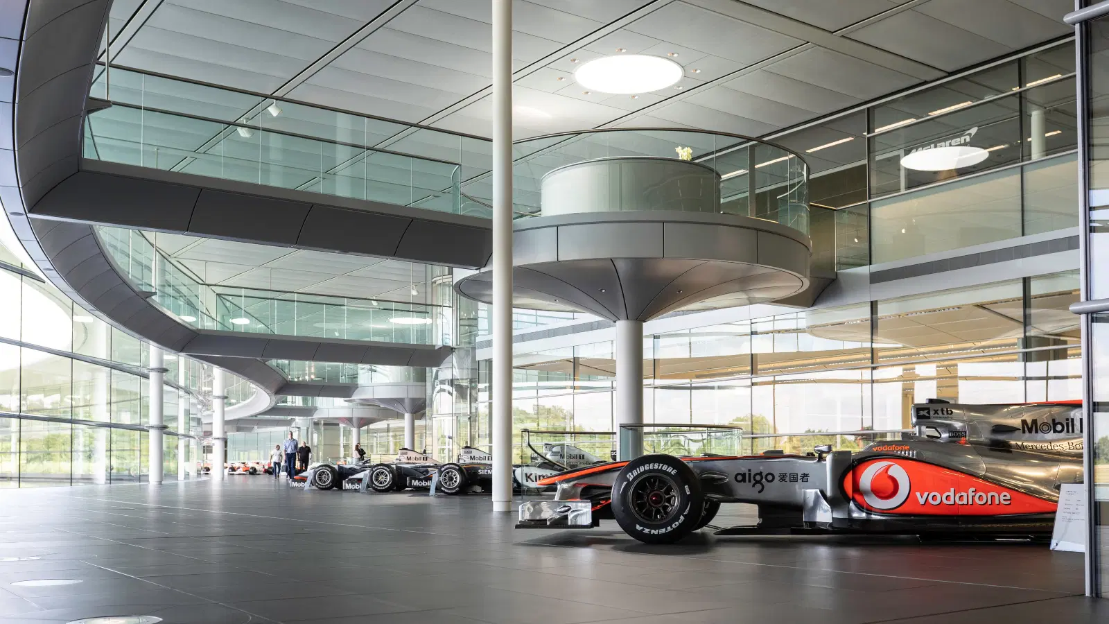 McLaren Technology Centre interior with Formula 1 cars displayed in a modern glass architecture workspace